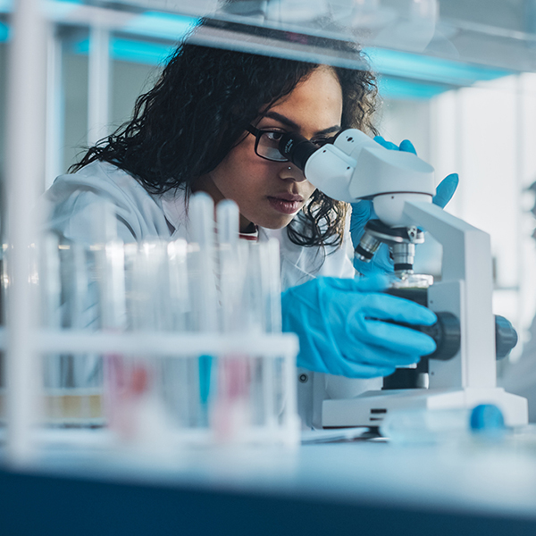 Black female scientist looking through a microscope