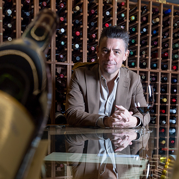 Hugo Duchesne sitting in a wine cellar with a glass of wine