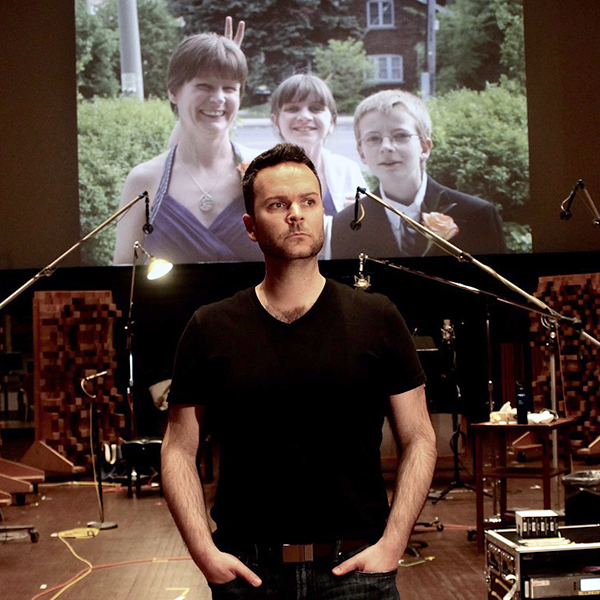 Joshua Hopkins, the co-creator of “Songs for Murdered Sisters,” with an image of his sister Nathalie Warmerdam and her children in the background (Photo: Zoe Tarshis)