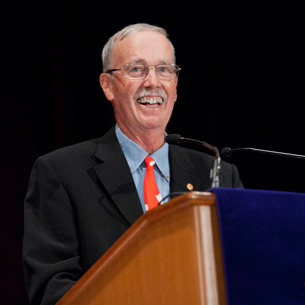 Derek Drummond smiling from behind a podium