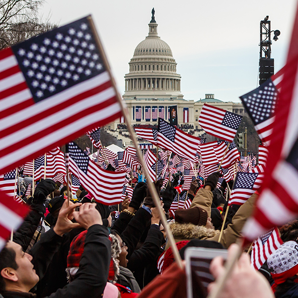 A crowd waving American flags in front of a government building
