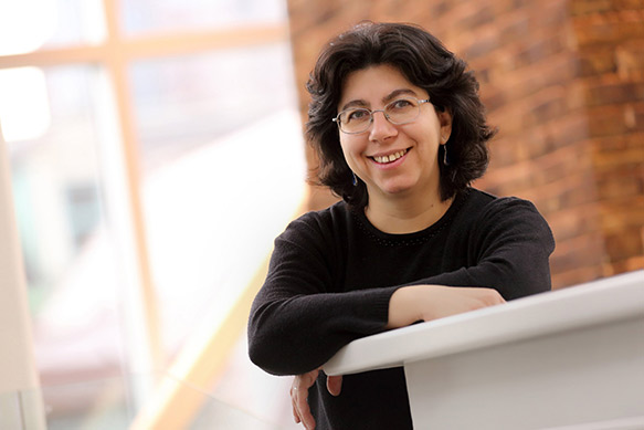 Doina Precup leaning on a counter, smiling