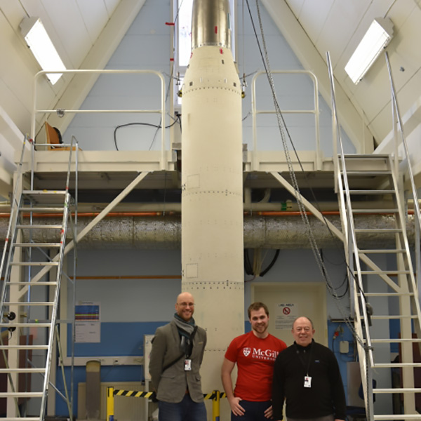 Andrew Higgins, Jan Palecka, and Samuel Goroshin standing in front of a rocket