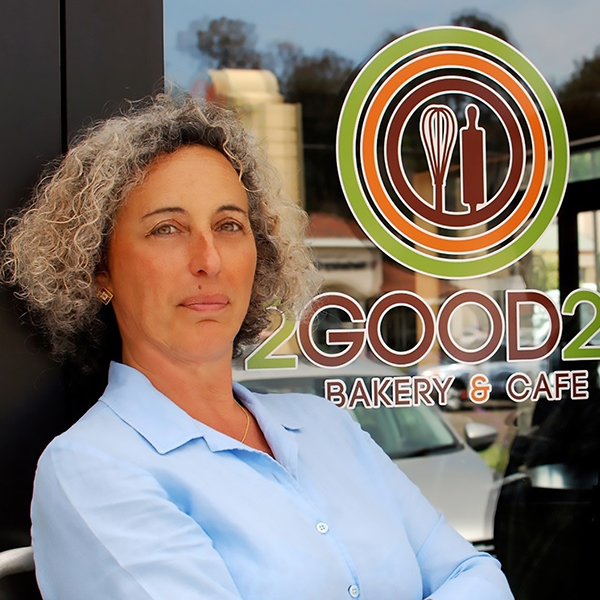 Diana Mourato Benedek sitting in front of the 2GOOD2B Bakery and Café