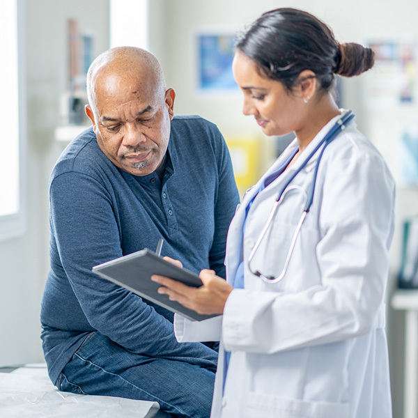 Female doctor showing an iPad to a male patient.