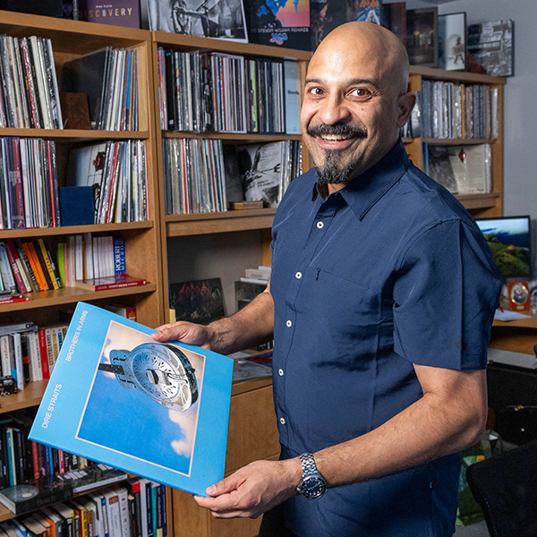 A person holding a record in front of a shelf full of books and records