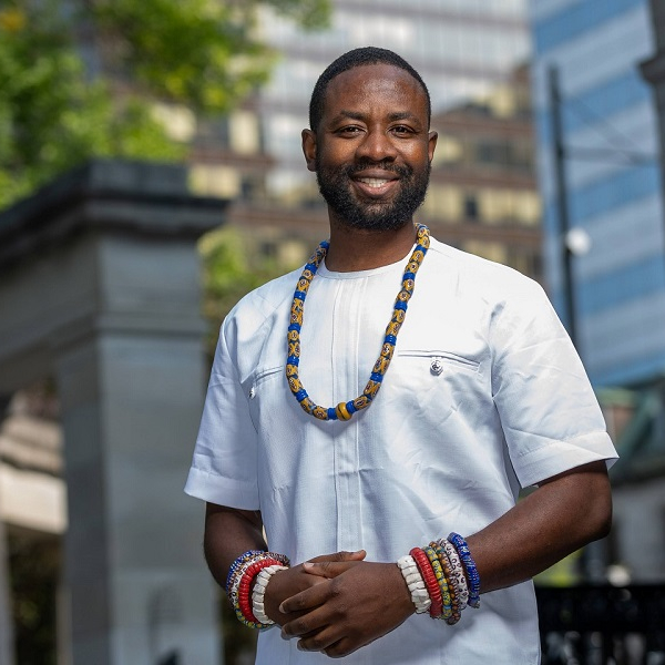 A person wearing a white shirt and a colorful necklace.