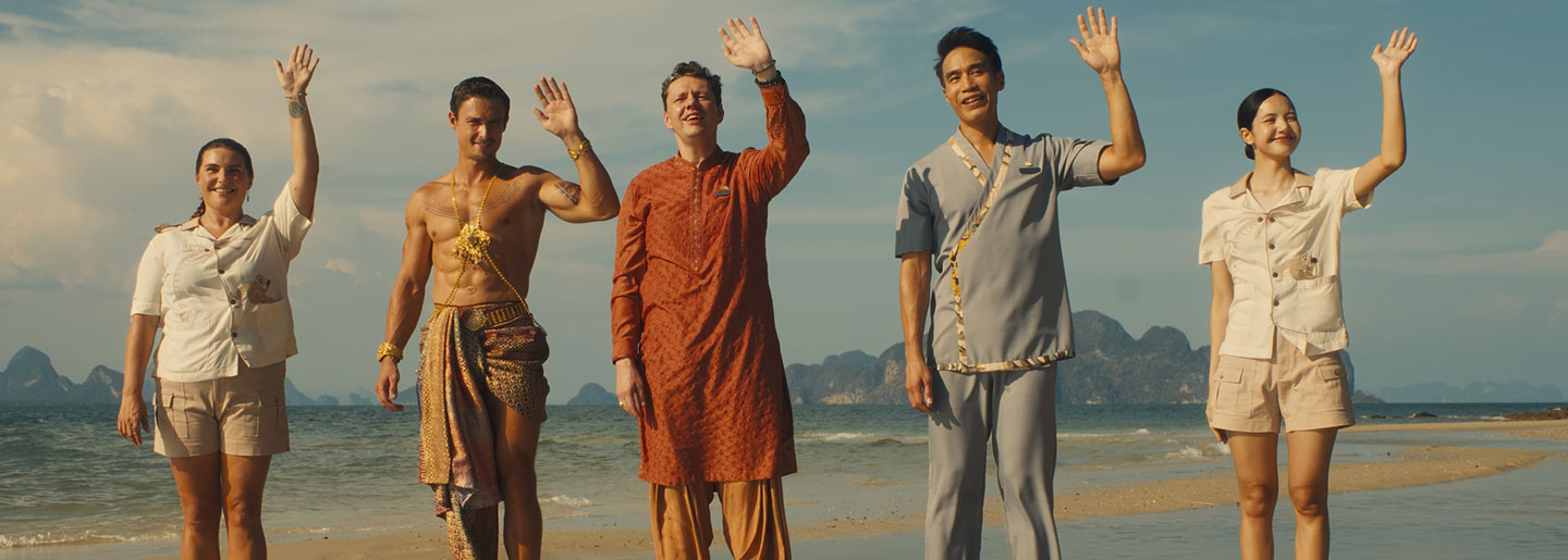 A group of people standing on a beach waving their hands.