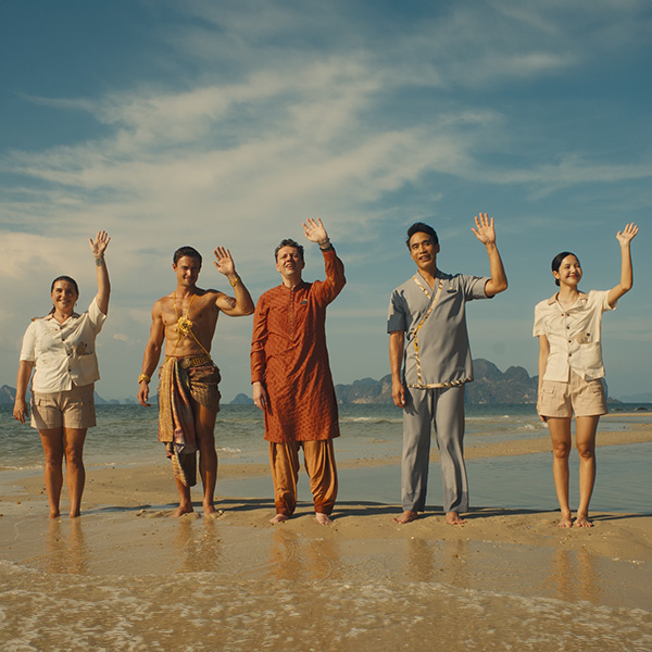 A group of people standing on a beach waving their hands.