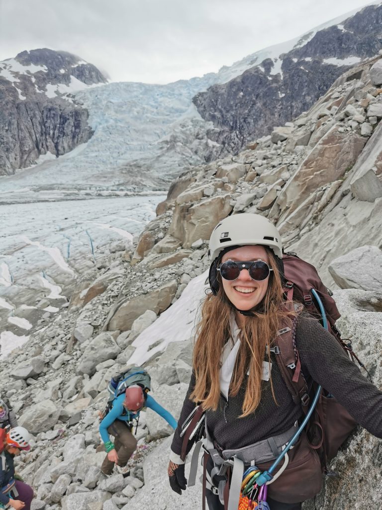 A person wearing a helmet and sunglasses on a rocky mountain.